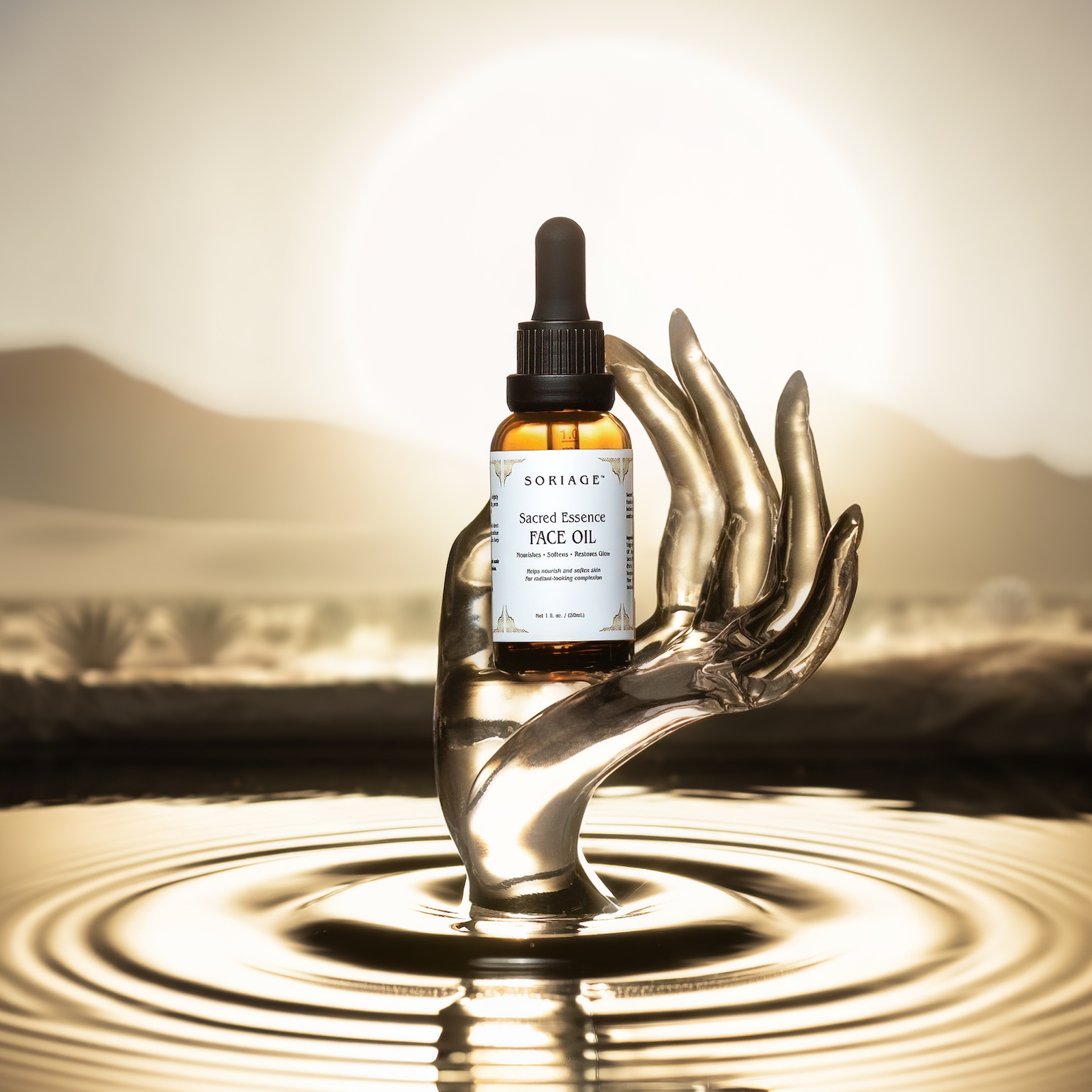 Bottle of face oil held by a metallic hand over water with a desert landscape in the background